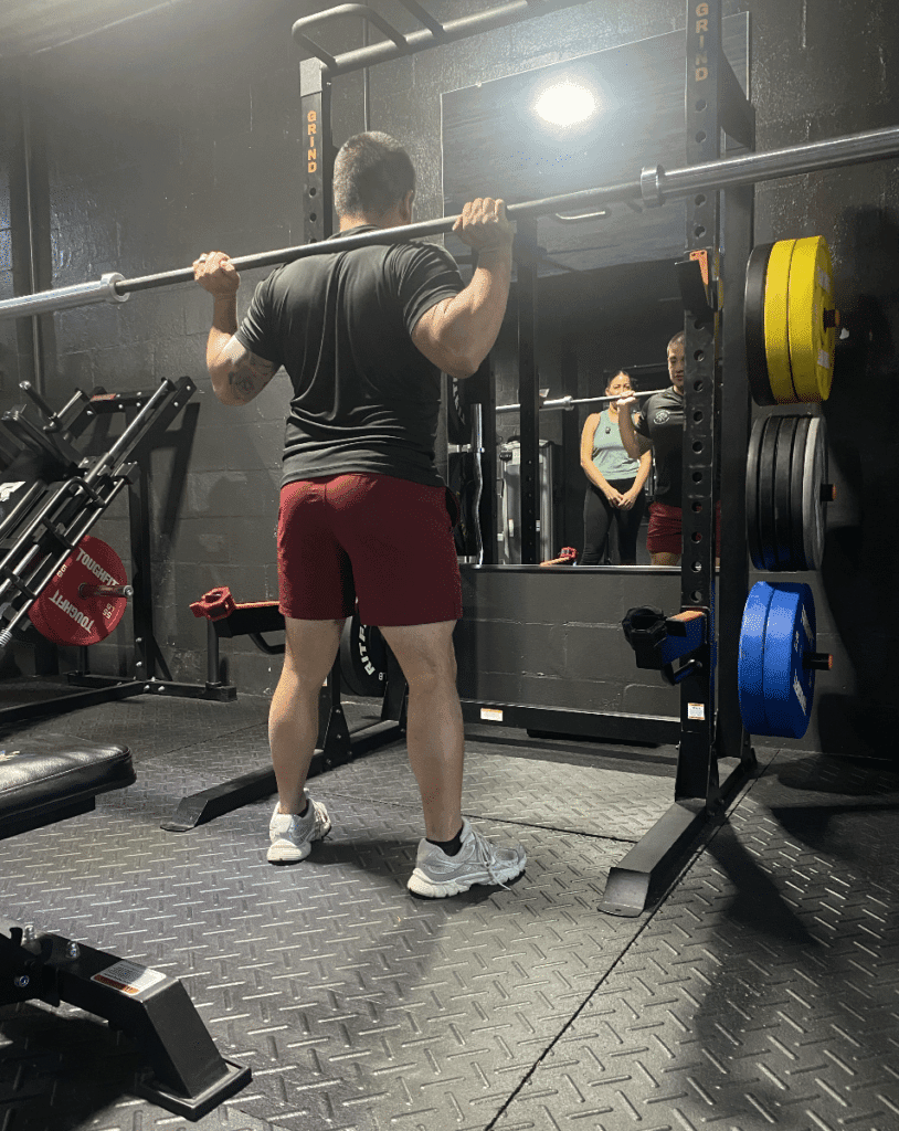 Personal Trainer showing client how to lift barbell at Prime Strength And Conditioning.